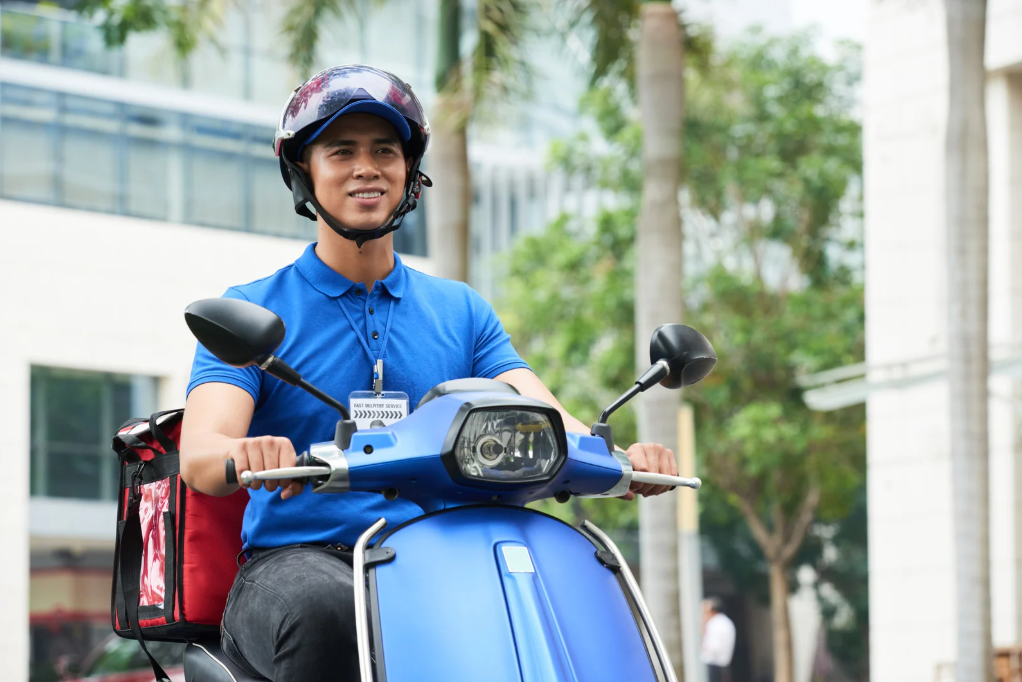 TheLex delivery rider in blue uniform on blue scooter - professional portrait